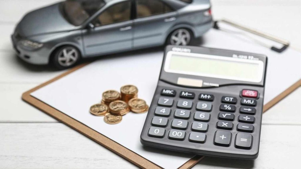 Calculator, coins, and a model car symbolizing car finance UAE costs and loan calculations.